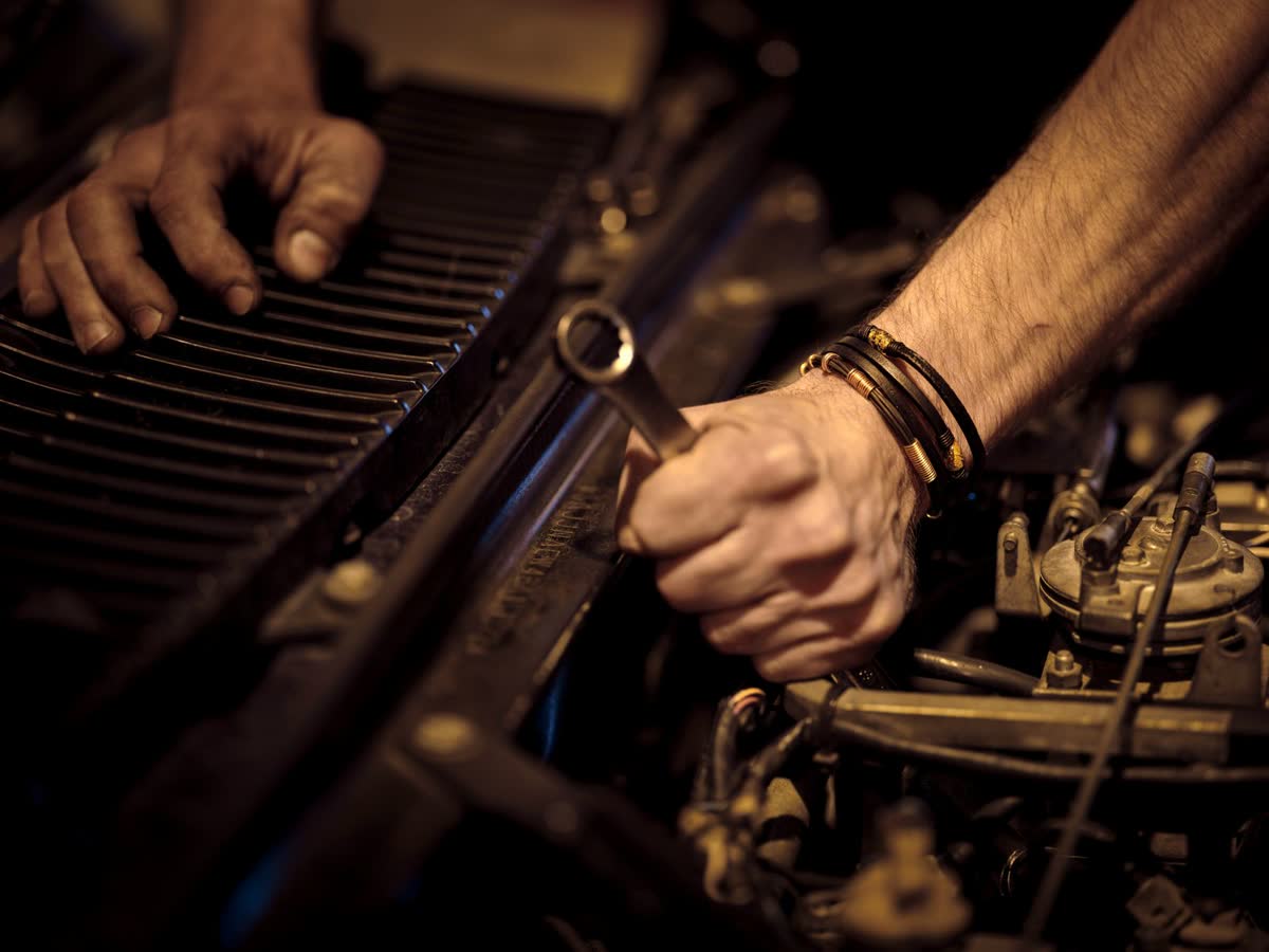 Mechanic working deep inside a car engine bay